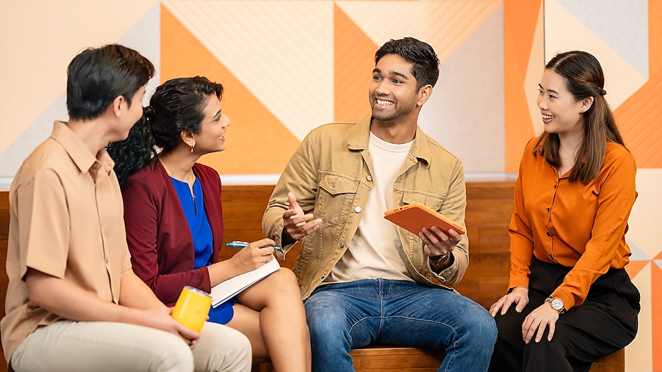 Four colleagues are sitting together, engaged in a candid discussion.