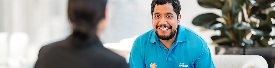 Male in blue shirt smiling to female sitting opposite him.