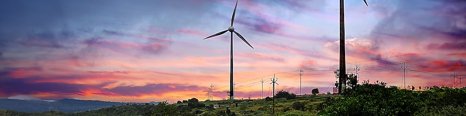 Two wind turbines with pink, purple and blue sunset background.